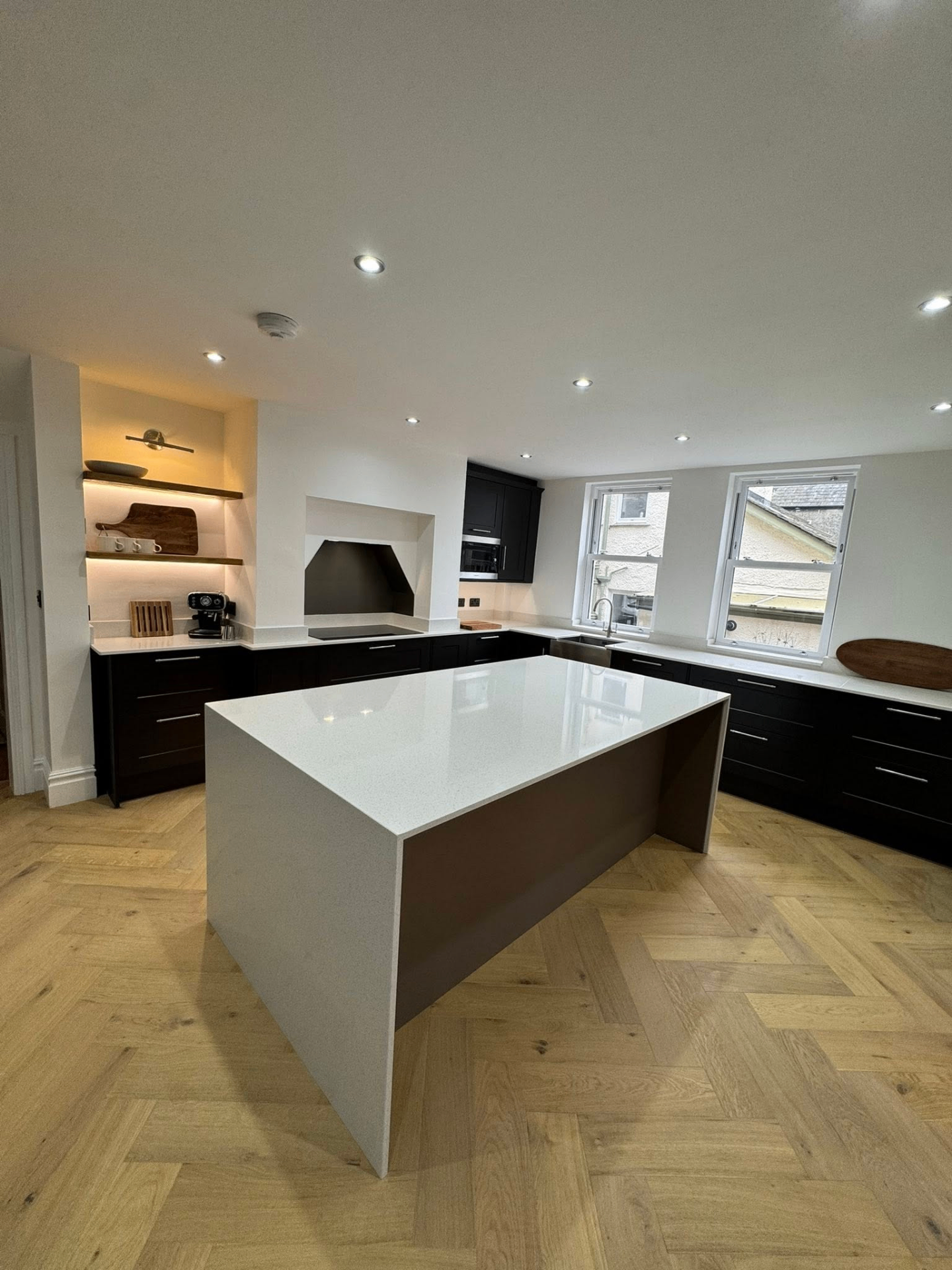 Black shaker kitchen with marble island and herringbone oak floor